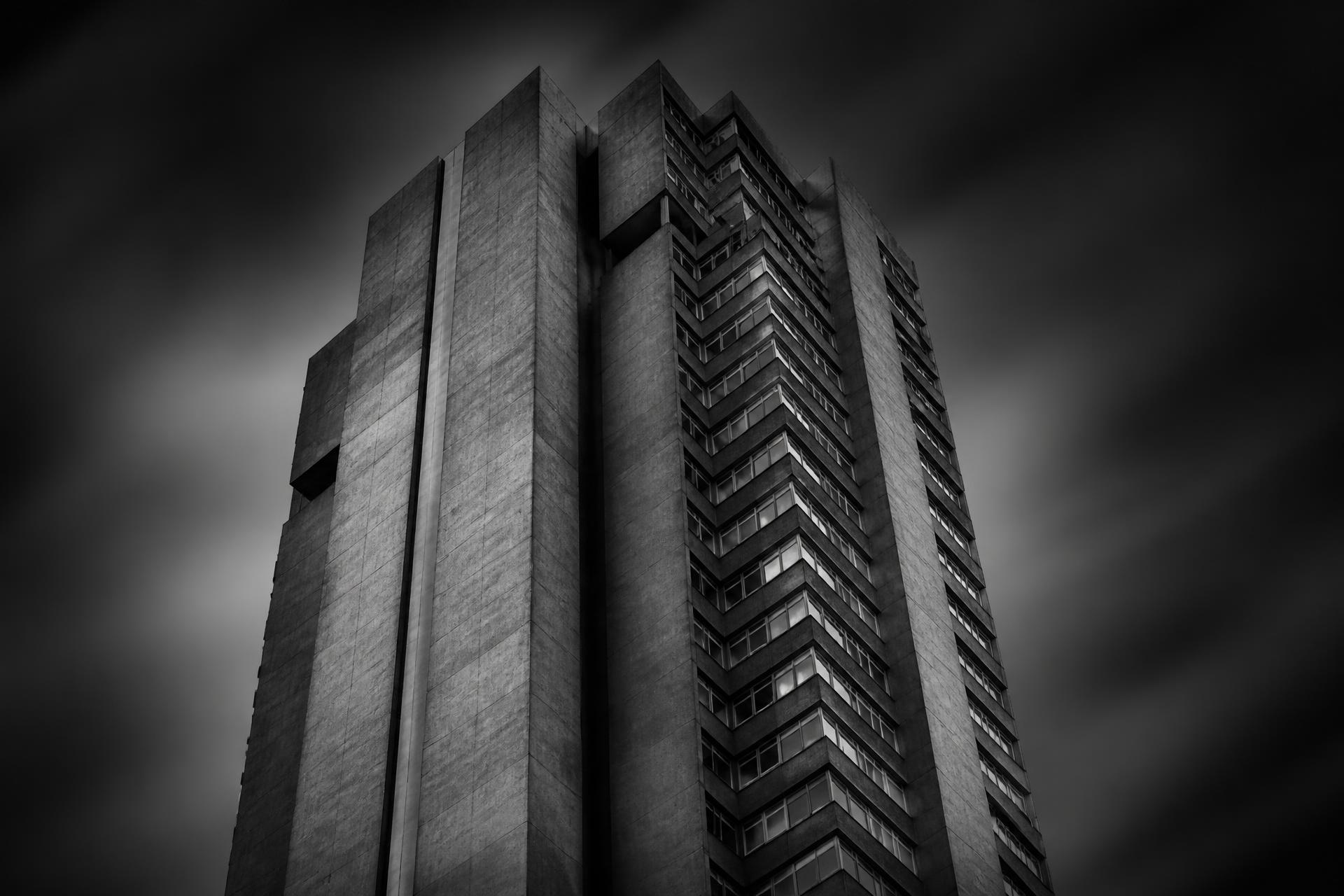 Monochrome low-angle photograph of a concrete tower against a dark sky